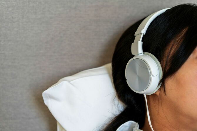ヘッドホンで音楽を聴きながらベッドに寝ている人