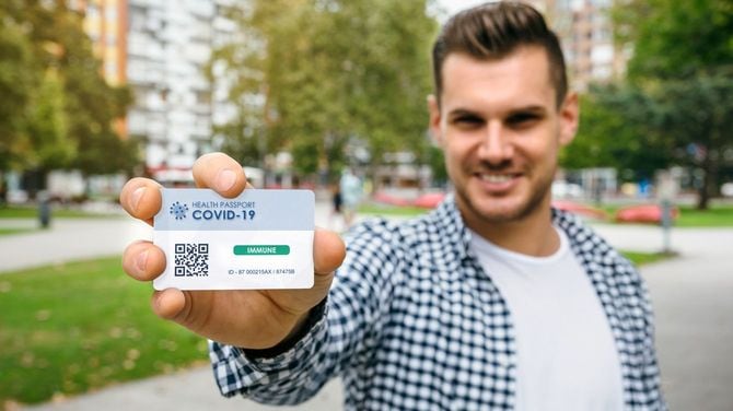コロナウイルスに免疫があることを示す健康パスポートを示す男性