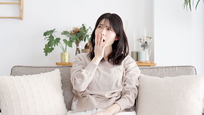 リビングのソファであくびをする女性