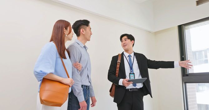部屋の内見でカップルに説明をする不動産業者