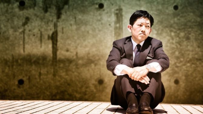 面倒くさくなってしまった日本人サラリーマンが体育座りで目をそらす