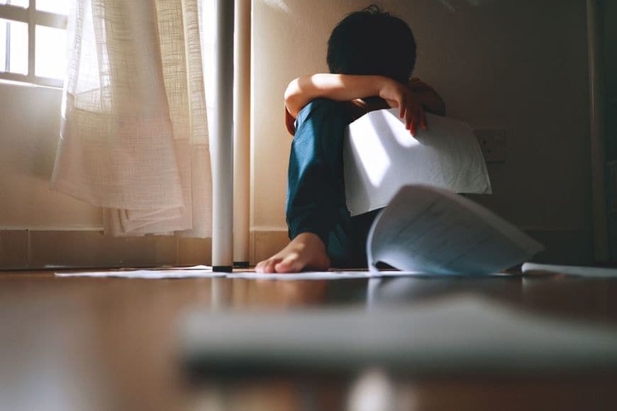 勉強のプレッシャーに落ち込んで座り込む少年
