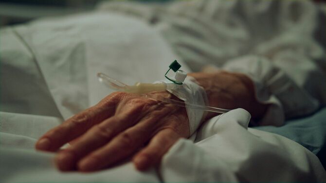 病棟でベッドに横たわる高齢患者