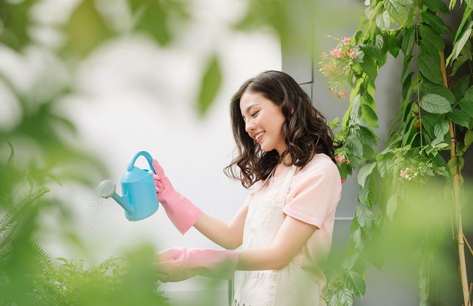 地上の庭でアジアの女の子ブルー散水