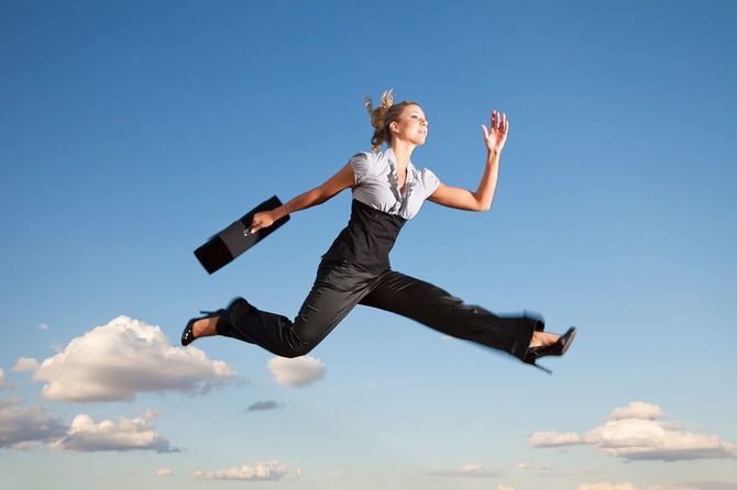 ビジネス鞄を持って空をかける女性