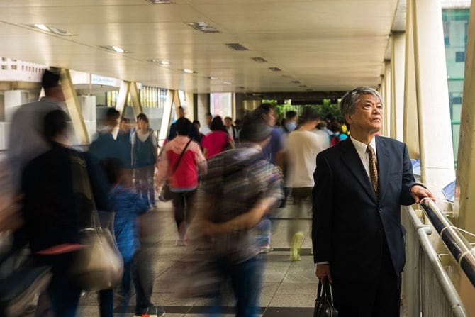 群衆の中から目立つアジア系の上級のビジネスマン