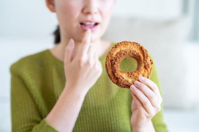 リビングルームでドーナツを食べる若い日本人女性