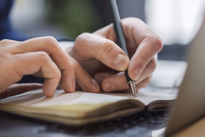 メモ帳にメモを書き留める男性の手