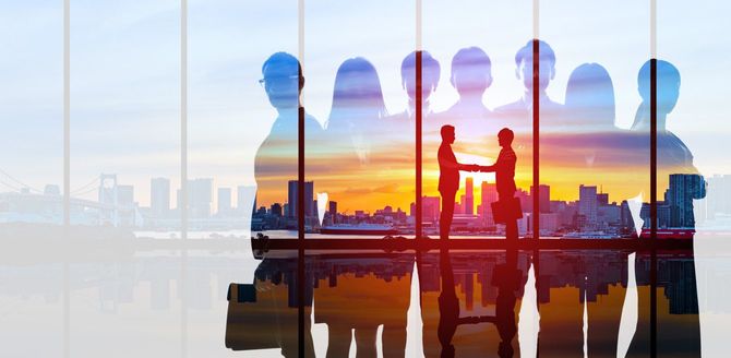 握手するビジネスパーソンと背景に夕焼け