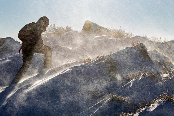 吹雪の中、登山をする人