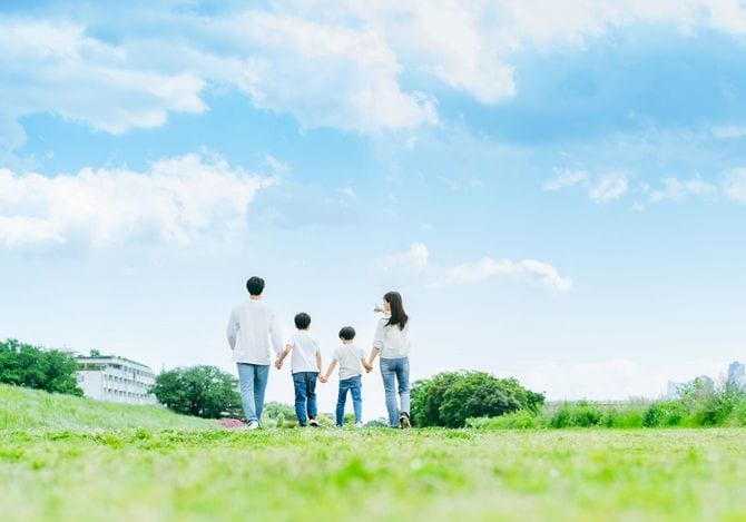 青空を背景に草原を歩く家族