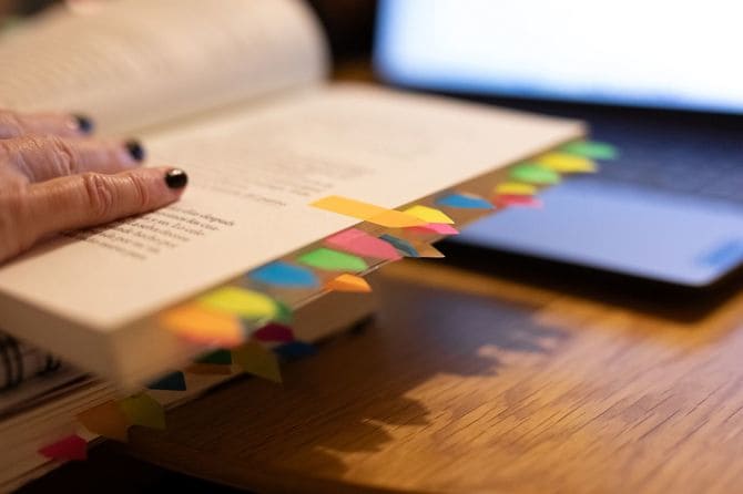 付箋をたくさん貼った本と高齢女性の手