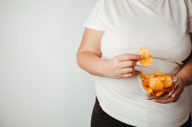 ポテトチップスを食べる太りすぎの女性