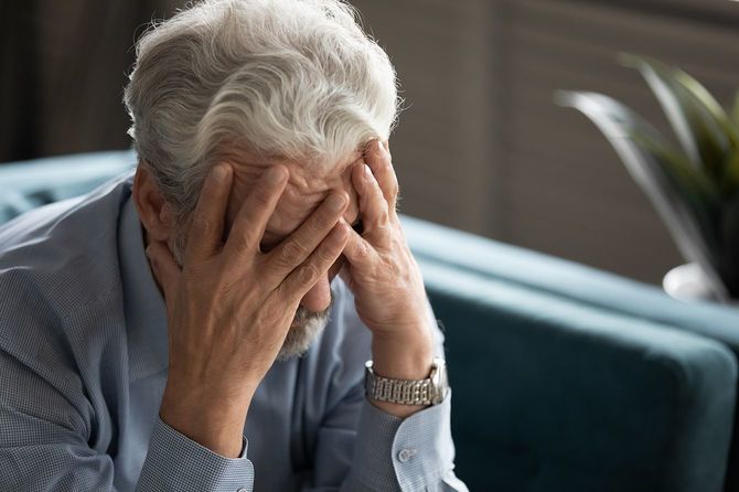 50代の男性は絶望的な顔を見て顔を隠し