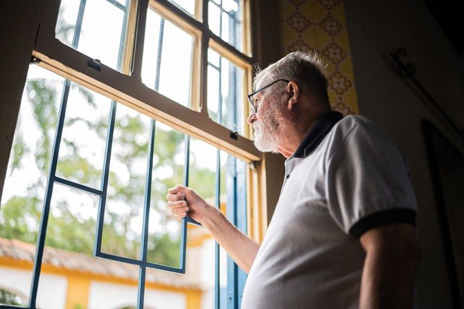 窓から外を覗く老人