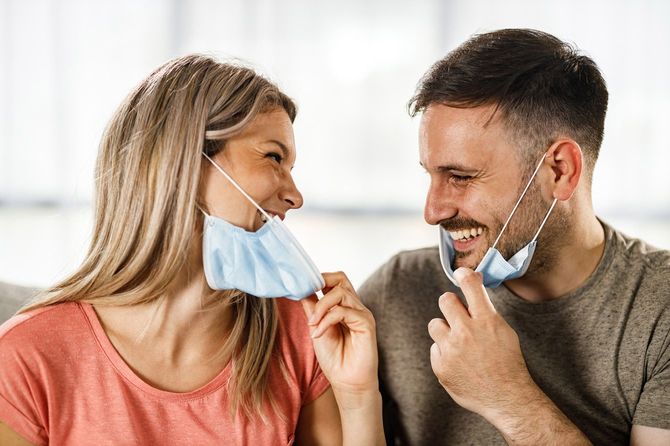 マスクをあごまで下げて微笑みあうカップル