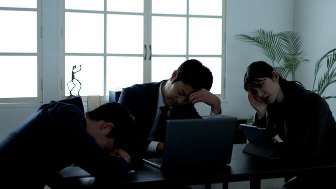 暗い会議室で憂鬱なビジネスパーソンたち