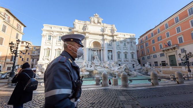 イタリア・ローマのトレビの泉広場を横切る、フェイスマスクをした警官（2020年3月10日）