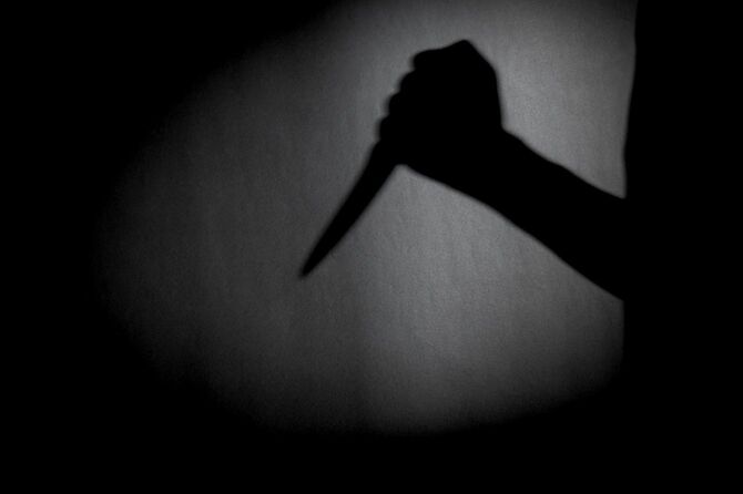 壁に映ったナイフを持つ人の影