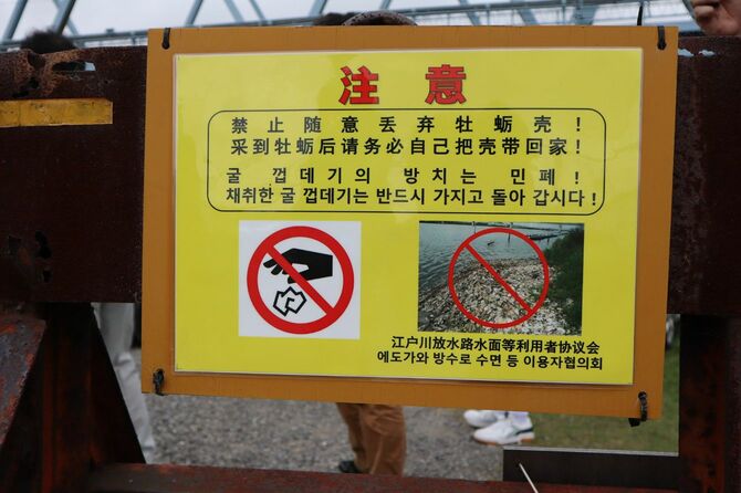 河川敷付近にはカキ殻の投棄を禁じる注意書きが多数。日本語のものもあるが、中国語の看板が特に目立つ。社会問題なのは間違いない。
