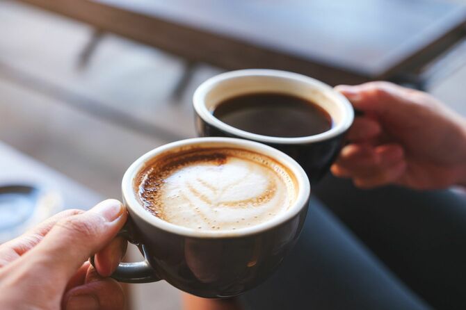 カフェでコーヒーの入ったカップを持つカップル