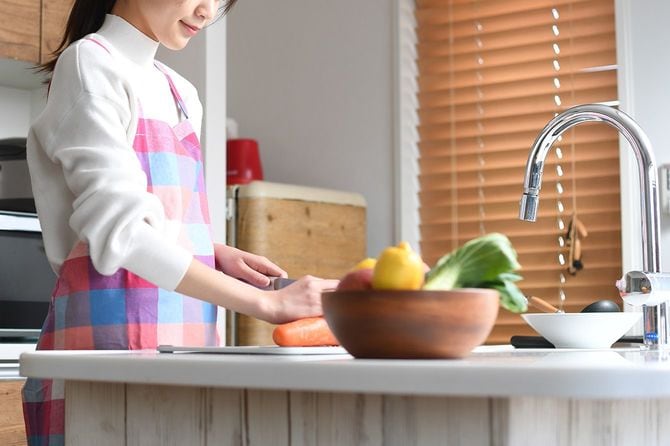 キッチンで野菜を切るエプロン姿の女性