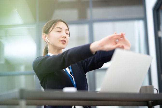 仕事の合間に腕を伸ばす人のイメージ
