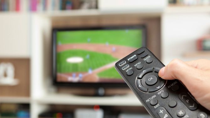 野球中継にチャンネルを合わせるリモコンを持った手