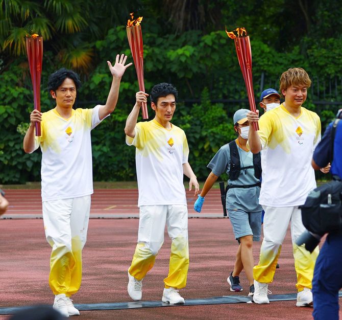 パラリンピック聖火到着式で、聖火を持って走る都内最終ランナーで国際パラリンピック委員会(IPC)特別親善大使の(左から)稲垣吾郎さん、草彅剛さん、香取慎吾さん=2021年8月24日午後、東京都渋谷区