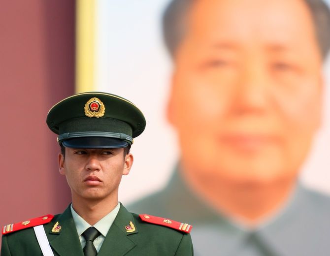 北京の天安門広場にて毛沢東の大きな肖像画の前で警備する中国の警察官