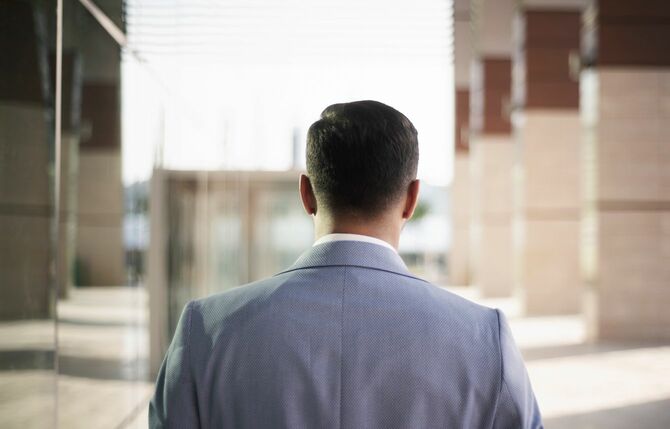 エントランスホールで人を待っている男性の後ろ姿