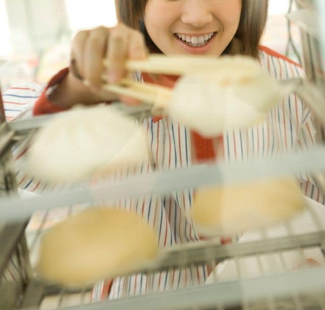 肉まんを取り出すコンビニエンスストアの店員