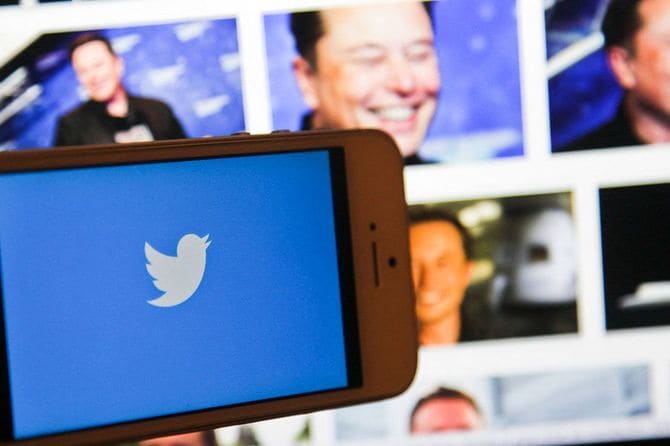 スマホ画面のツイッターのロゴと、パソコン画面に映ったイーロン・マスク氏の顔=2022年11月8日、フランス