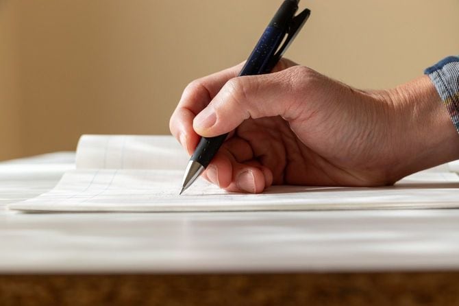 ノートにメモを取る人の手の側面図