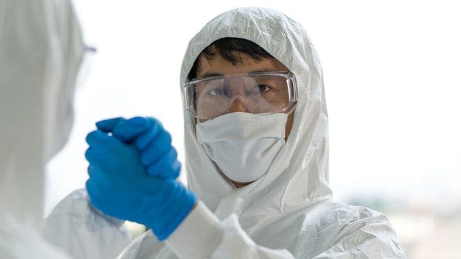 ウイルス防護服に身を包んだ疫学研究者が実験終了後に互いを祝福し合っている