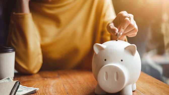 貯金箱に硬貨を入れる女性の手元