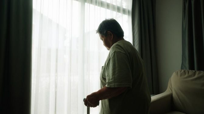 窓の外を見ている杖を持った高齢者