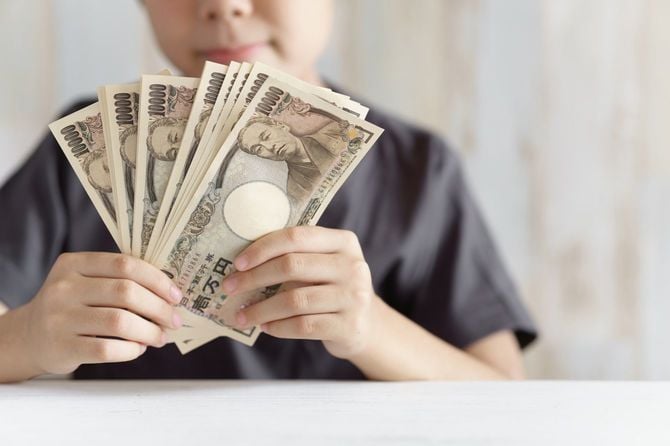 給付金の10万円を手に持つ男児