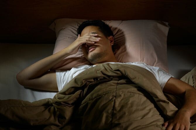 ベッドで不眠症に苦しんで落ち込んでいる男