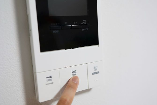 ドアホンの通話ボタンを押している手元