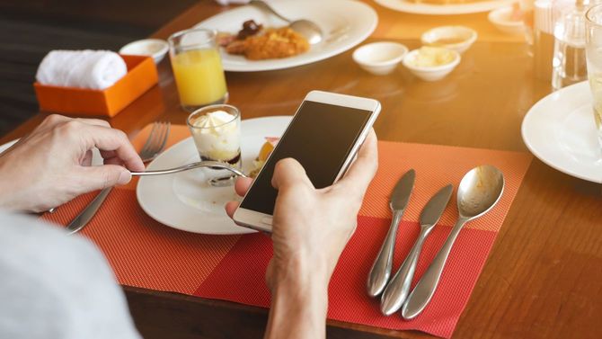 レストランでの食事中にスマホを操作する男性の手元