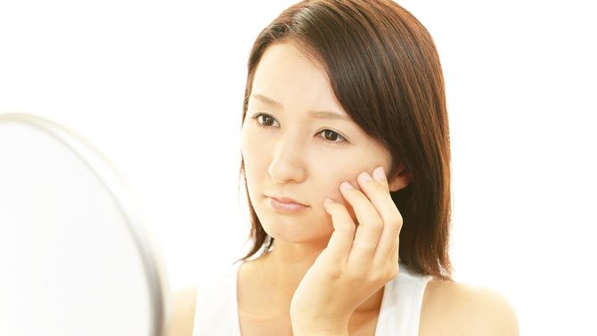 手鏡で自分を見つめる女性