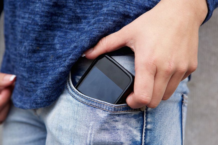 ジーンズポケットから携帯電話を取り出す手元