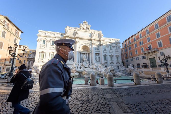 2020年3月10日、イタリア・ローマの閑散としたトレビの泉の広場を、フェイスマスクをつけた市警の男性が歩いている。