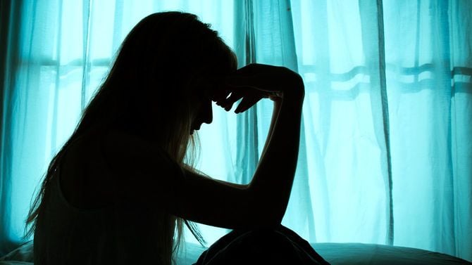 ベッドサイドに座り込む女性のシルエット