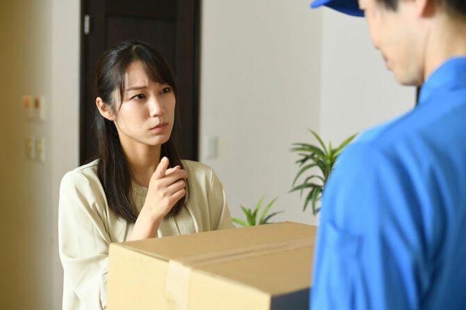 段ボールを持った配達員に怒る女性