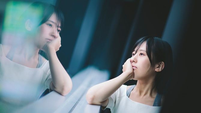 窓辺で頬杖をつき、考え込む女性
