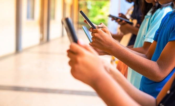 学校の廊下でスマホを使用する子供たち