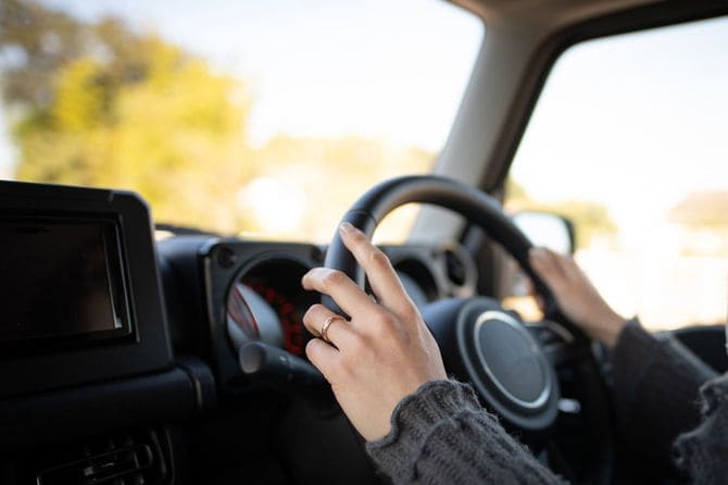 車のハンドルを握る結婚指輪をした手