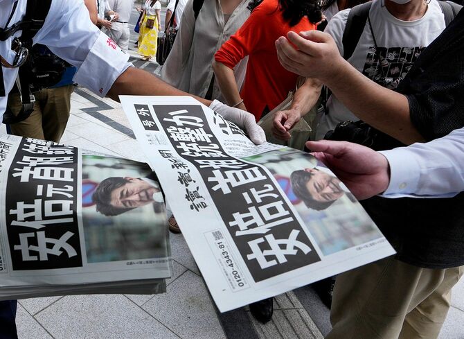安倍晋三元首相の銃撃を伝える新聞号外を手にする人たち。東京都内で2022年7月8日撮影